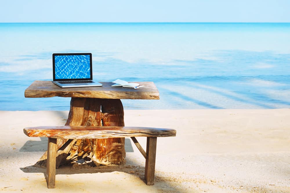 مكان العمل - حاسوب محمول على طاولة على الشاطئ